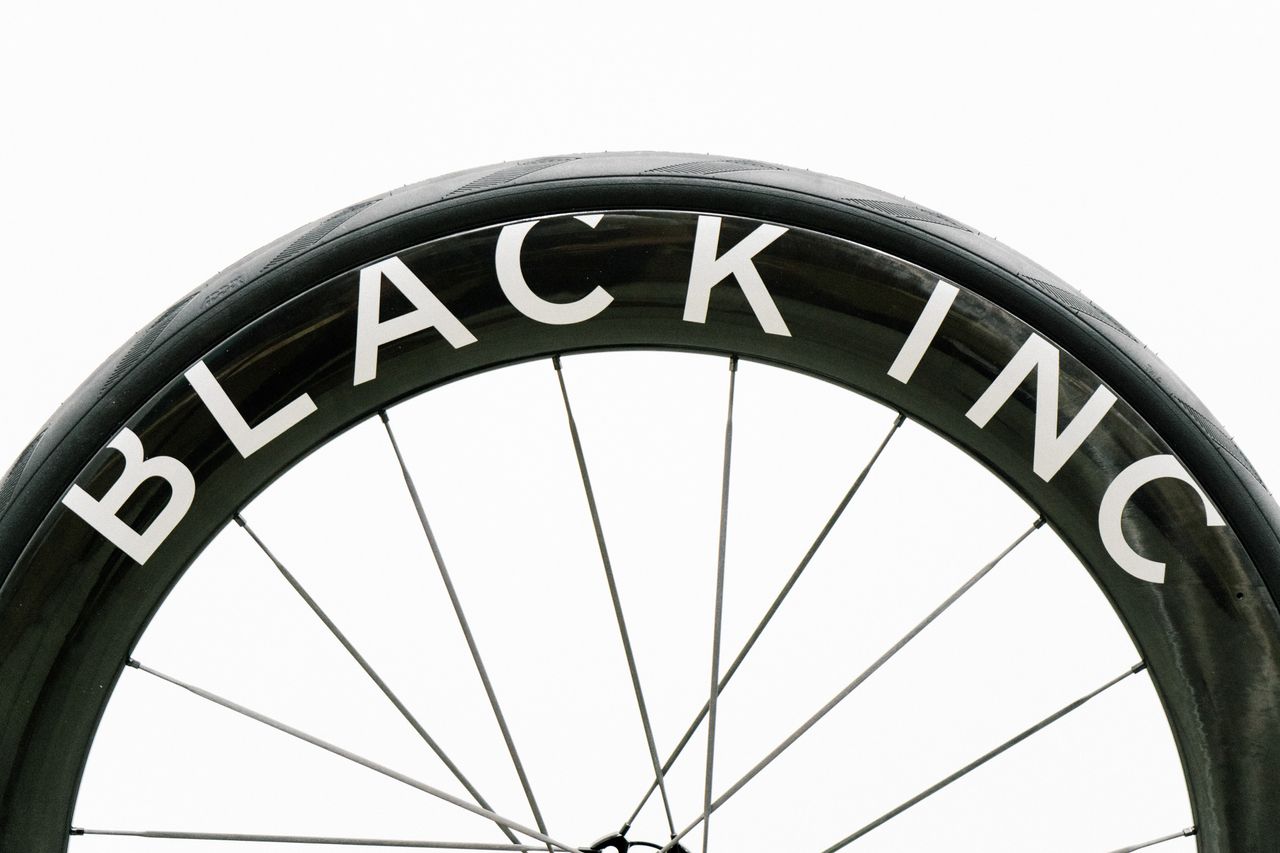 An aero road wheel stands against a white wall
