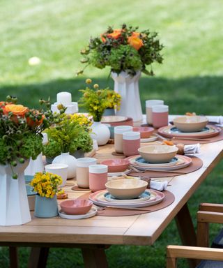 An al fresco table set with floral arrangements and colorful dishes