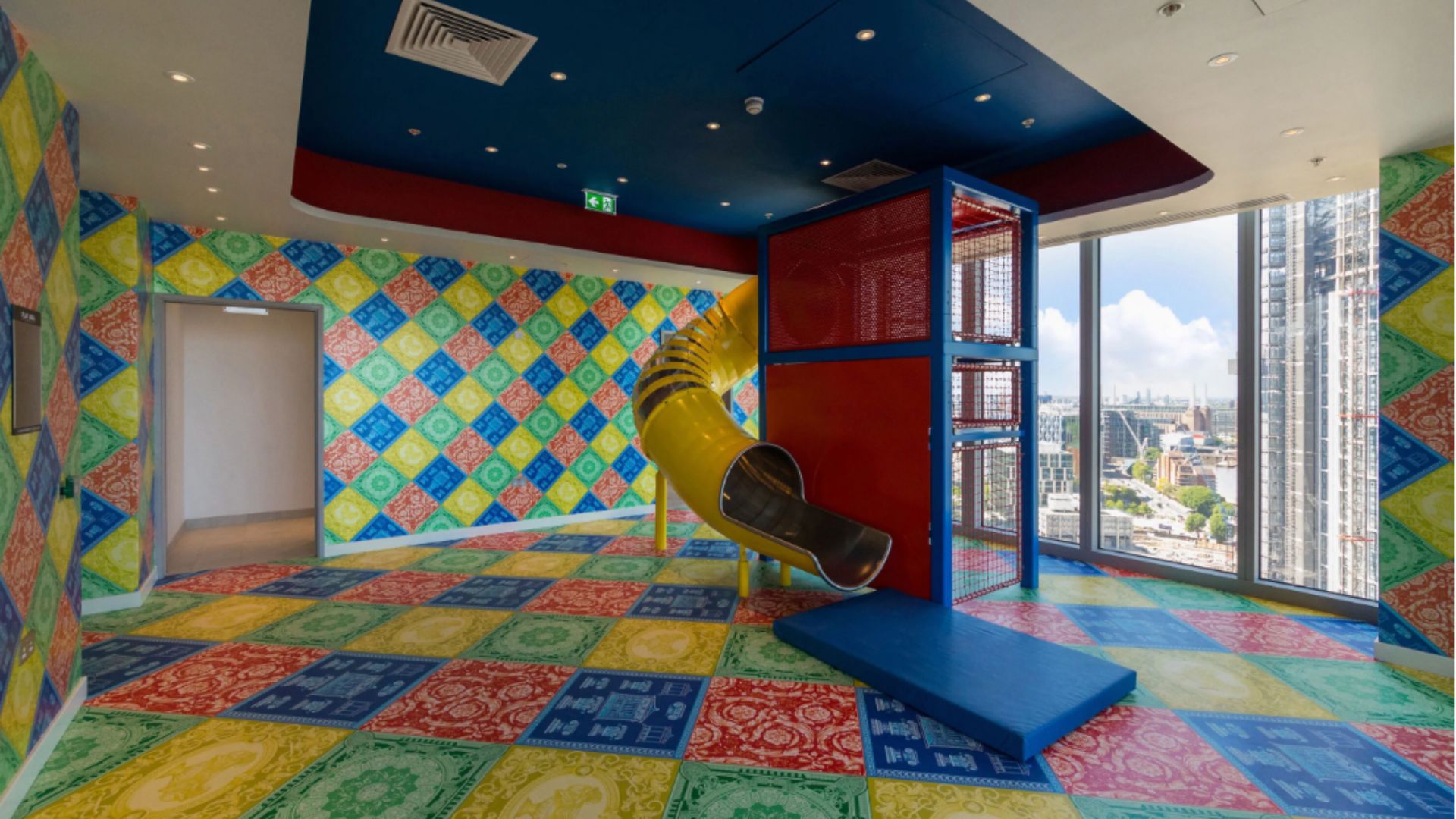 an image of the second playroom which also has a yellow tube slide and mutlicoloured mosaic style floor