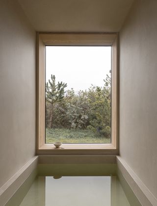 view of nature through rectangular window at Heatherhill Beach house by Norm Architects