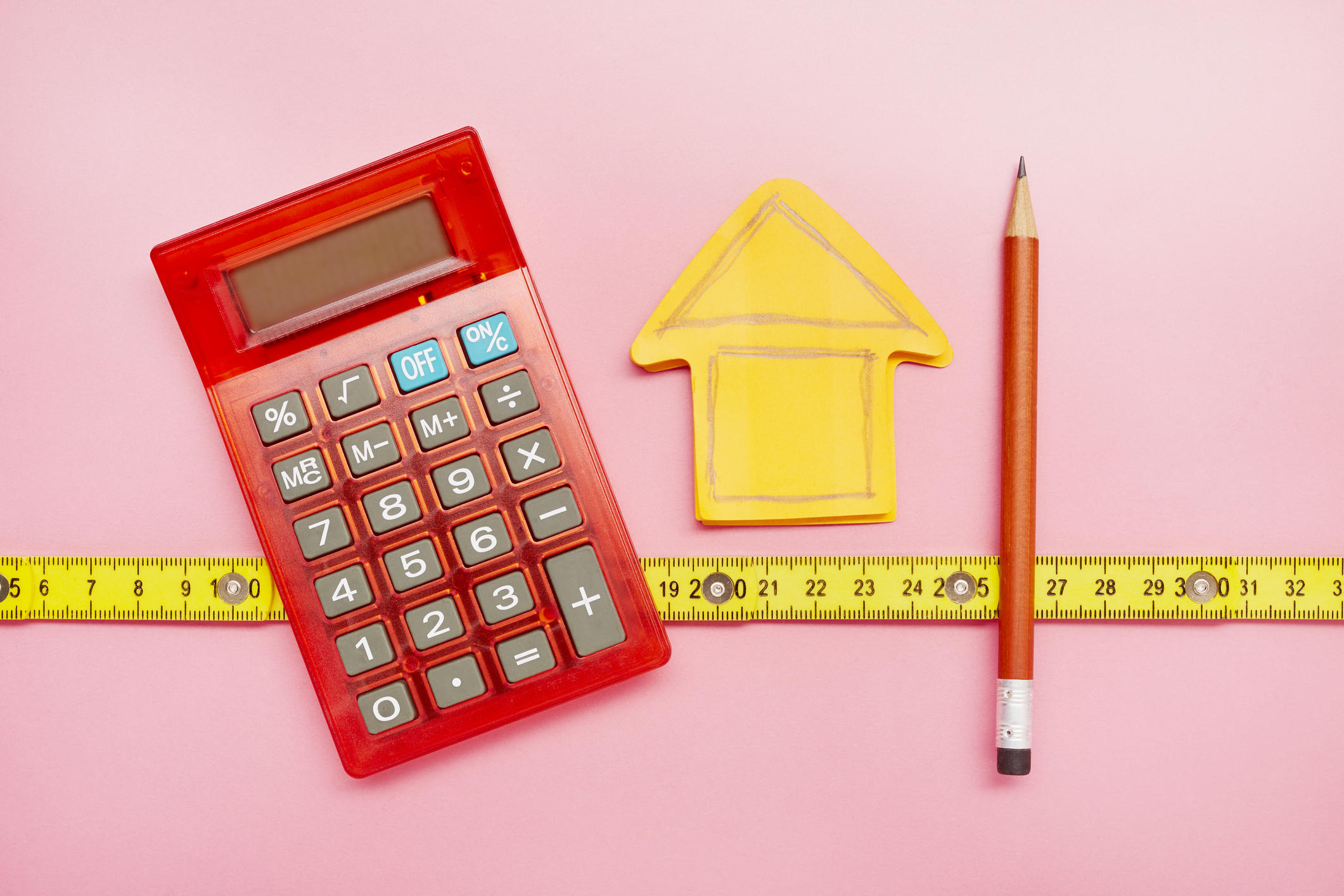 yellow paper house with a pencil, calculator, and measuring tape
