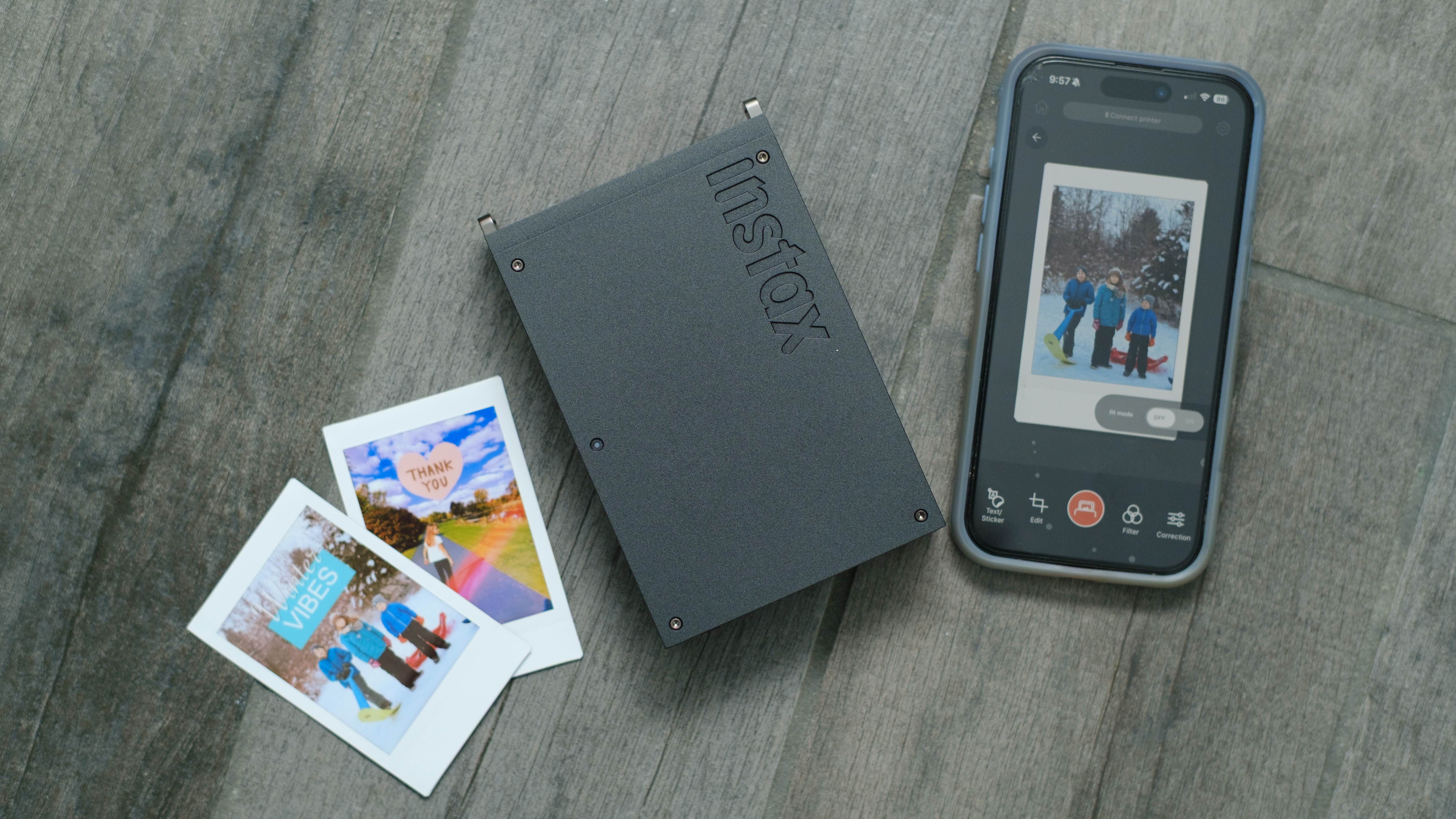 The Fujifilm Instax Mini Link+ on a gray background with instant prints