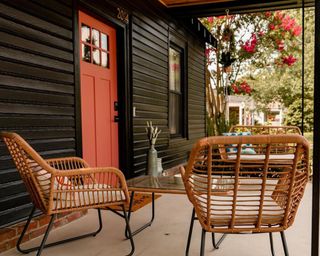 Black and coral front porch idea with rattan furniture