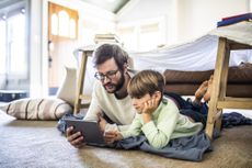 Father and son watching digital tablet in homemade fort