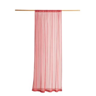 A red curtain panel hanging on a wooden rod