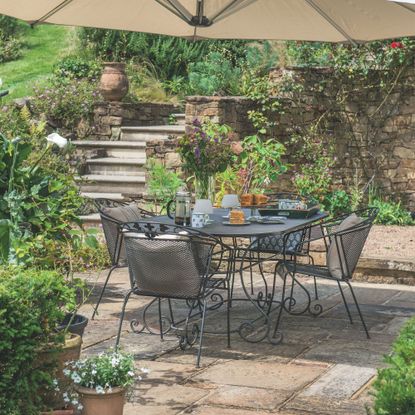 Metal garden furniture in garden patio area surrounded by potted plants