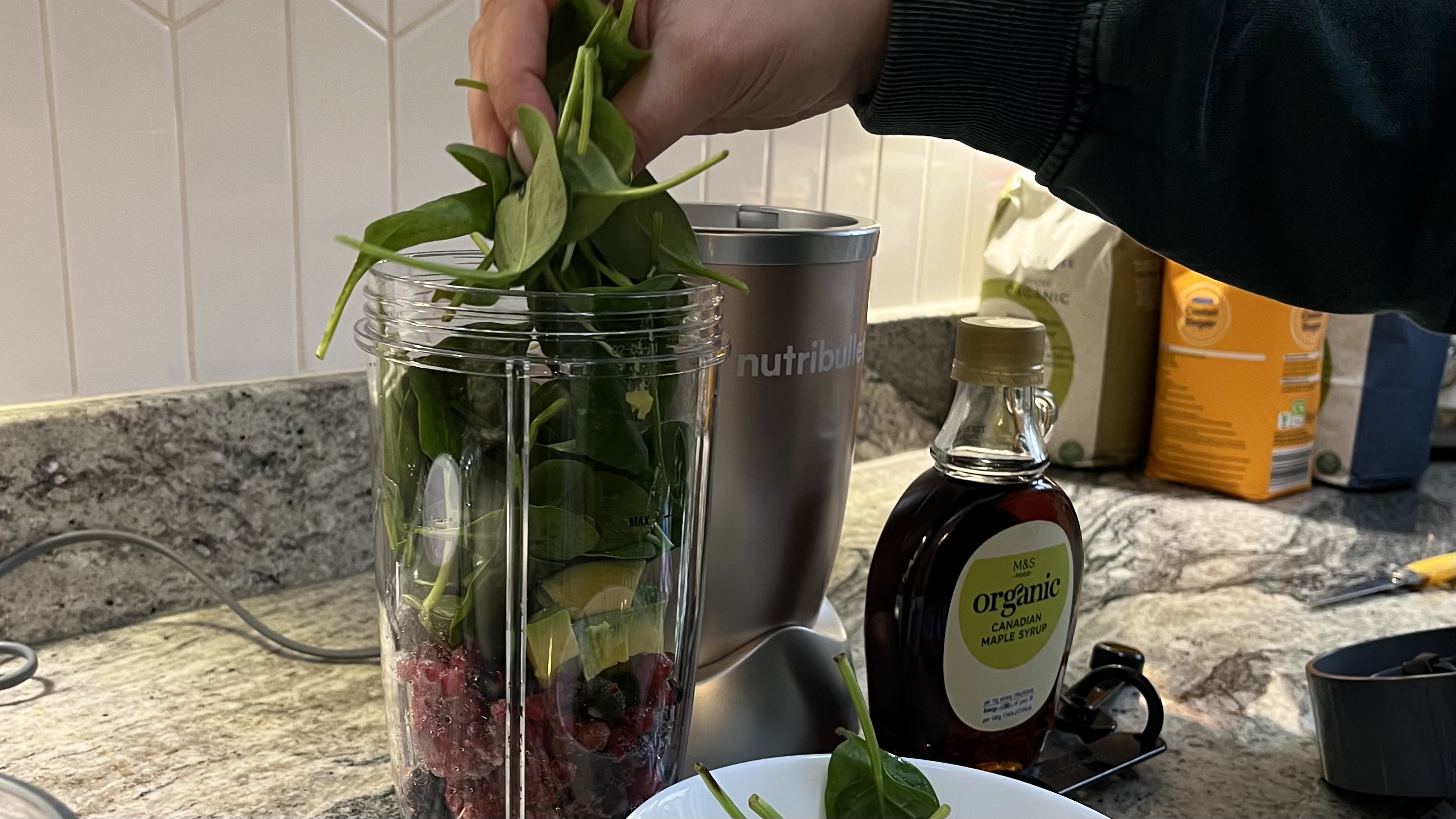 Nutribullet Pro 900 next to maple syrup with spinach in the chamber