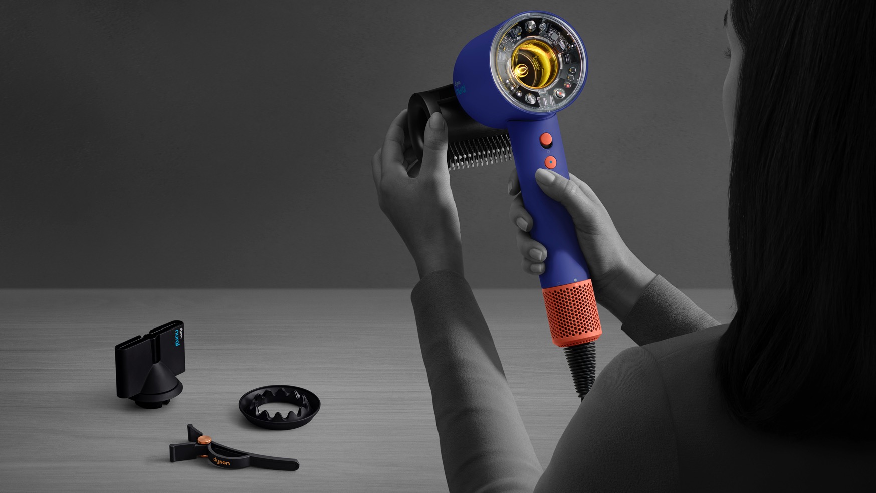 A woman adding an attachment to the Dyson Supersonic Nural hair dryer