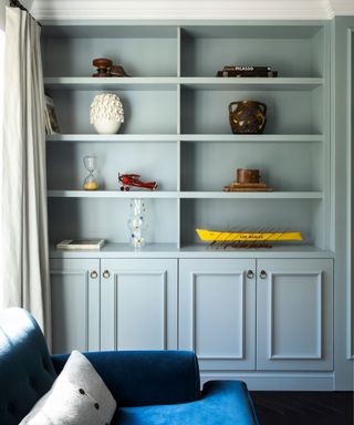 Living room detail with fitted light blue-grey cabinet in alcove, decorated with decorative ornaments and vases