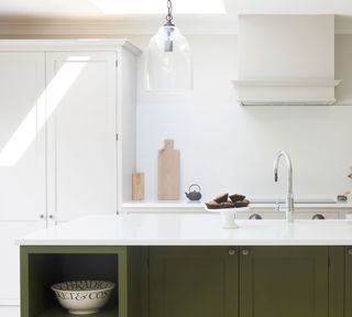 Shaker style kitchen with skylight and olive green island with white counter and white cabinets and walls