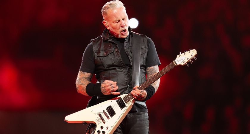 James Hetfield of Metallica plays his iconic white V-style live onstage, wearing his trademark black T-shirt, and black leather vest.