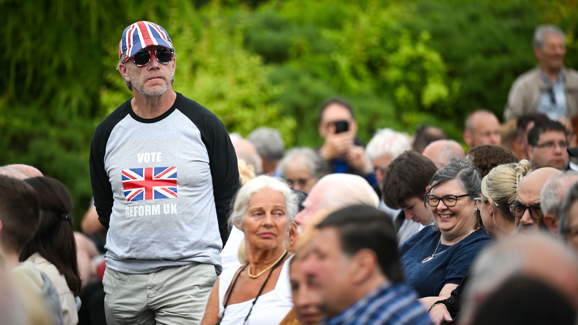 Reform supporters waiting for Reform UK leader Nigel Farage to speak during an election campaign event at Trago Mills, Devon