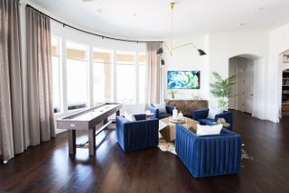 media/games room with small pool table, blue armchairs, tv , pendant light, coffee table, side table, hardwood floor