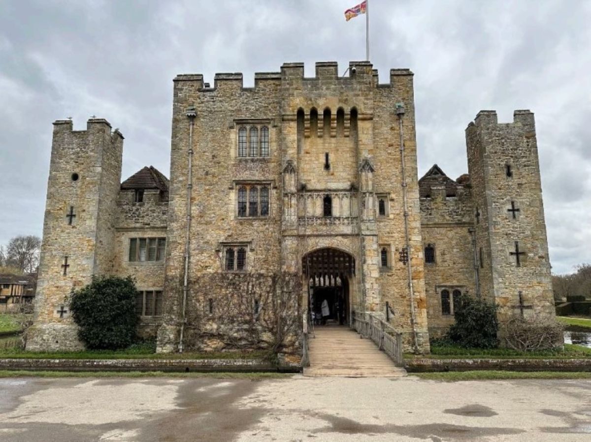 The front of Hever Castle shows a stone structure castle with plants growing up the walls