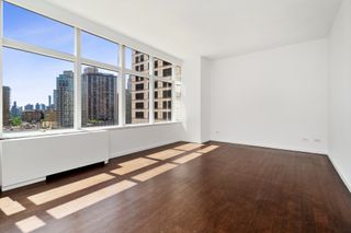 An empty room in an apartment with white walls and wooden flooring