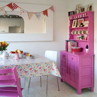 kitchen dinner room with white wall and pink cabinet