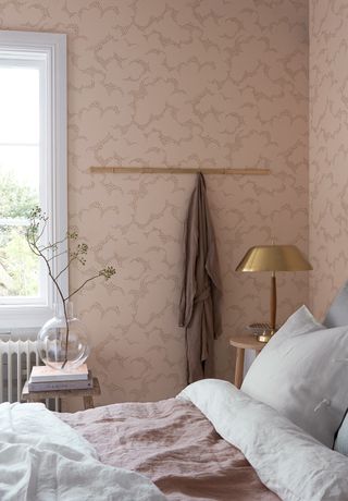 Soft pink bedroom wallpaper by Boras Tapeter with gold accents and white linen bedding