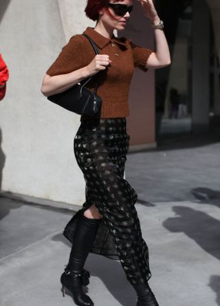 Woman wearing a cropped brown polo shirt and long black skirt