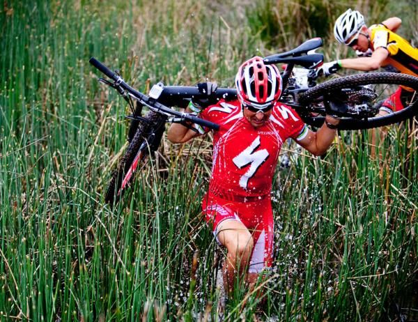 Christoph Sauser shoulders his bike
