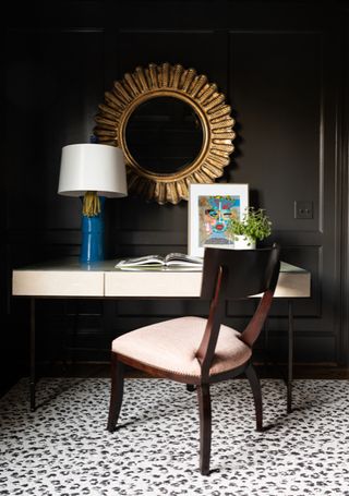 desk and side chair with desk lamp and gold framed mirror