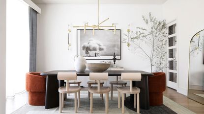 White dining room with mixture of upholstered chairs and impressive lighting ceiling fixture in brass