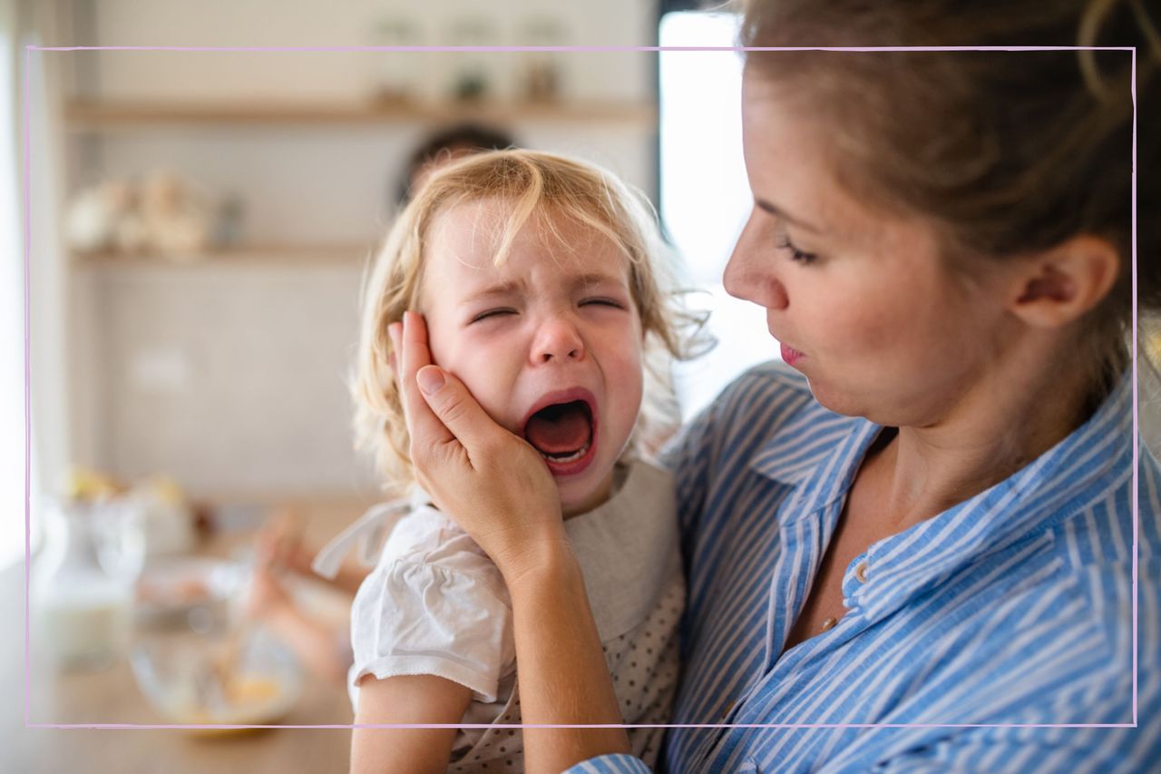 A woman carrying a crying toddler