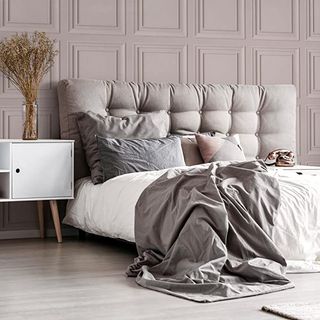 Grey and white bed with blush panelled wallpaper behind