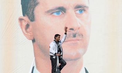 A protester stands in front of an oversized poster of President Bashar al-Assad: Opposition leaders say Monday's municipal elections were "utterly meaningless."