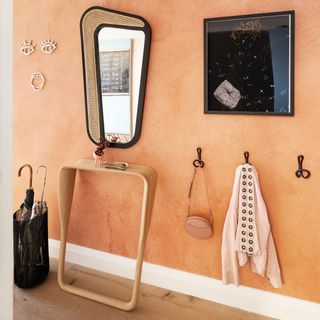 Bright orange entryway with modern mirror, wall decor, and hooks