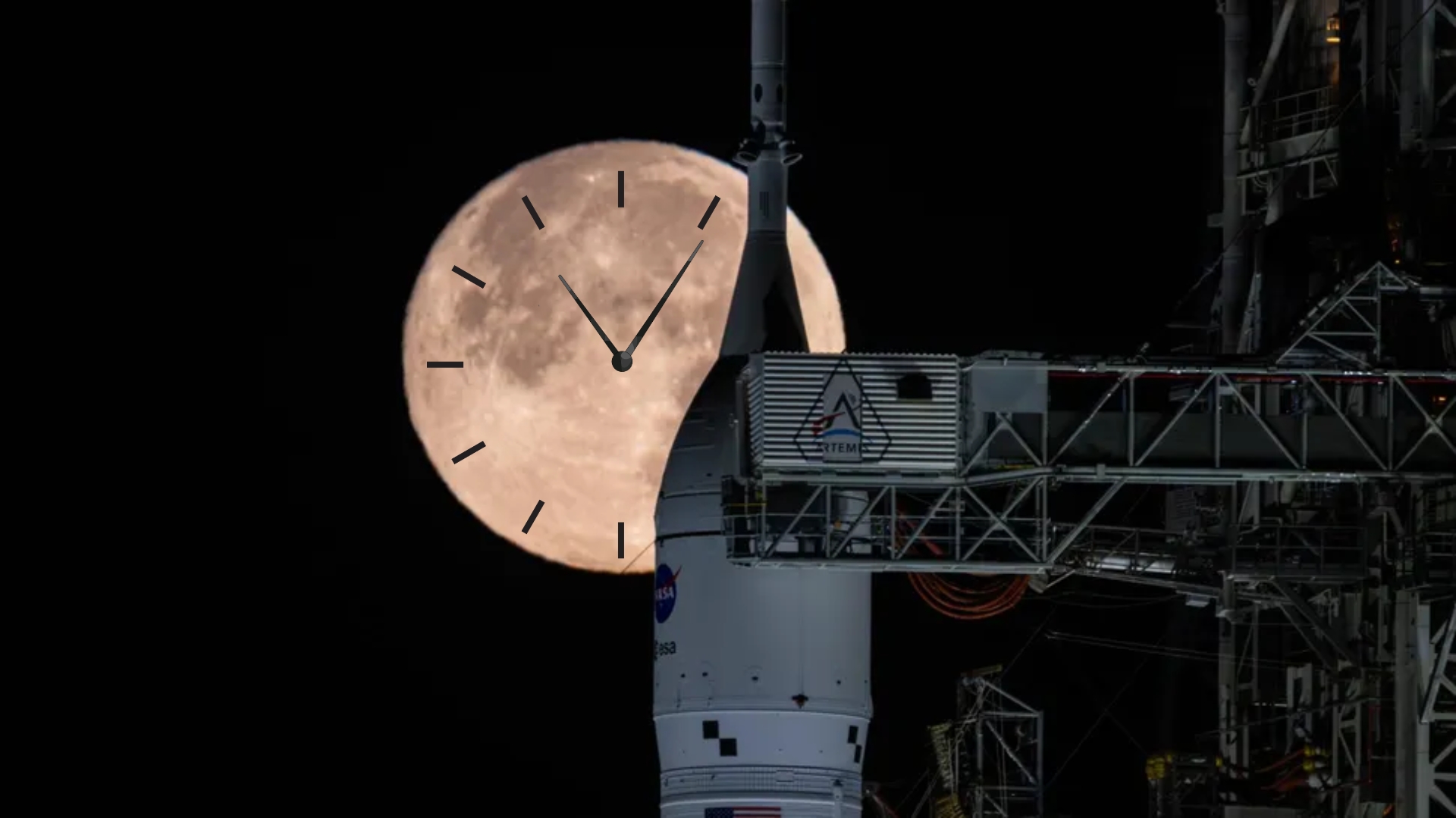 A white rocket nose with the circular NASA logo stands next to the metal gantry underneath a glowing large full moon in a black night sky. There is a graphic of a clock on the moon to convey the what time is Artemis 2l launch.