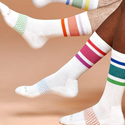 Two pairs of legs wearing colourful white striped socks.