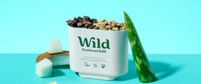 Deodorant refill cup filled with rocks next to a coconut