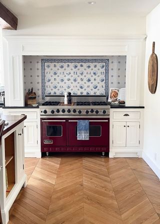 Dutch tile blue and white on backsplash behind purple cooker in white kitchen