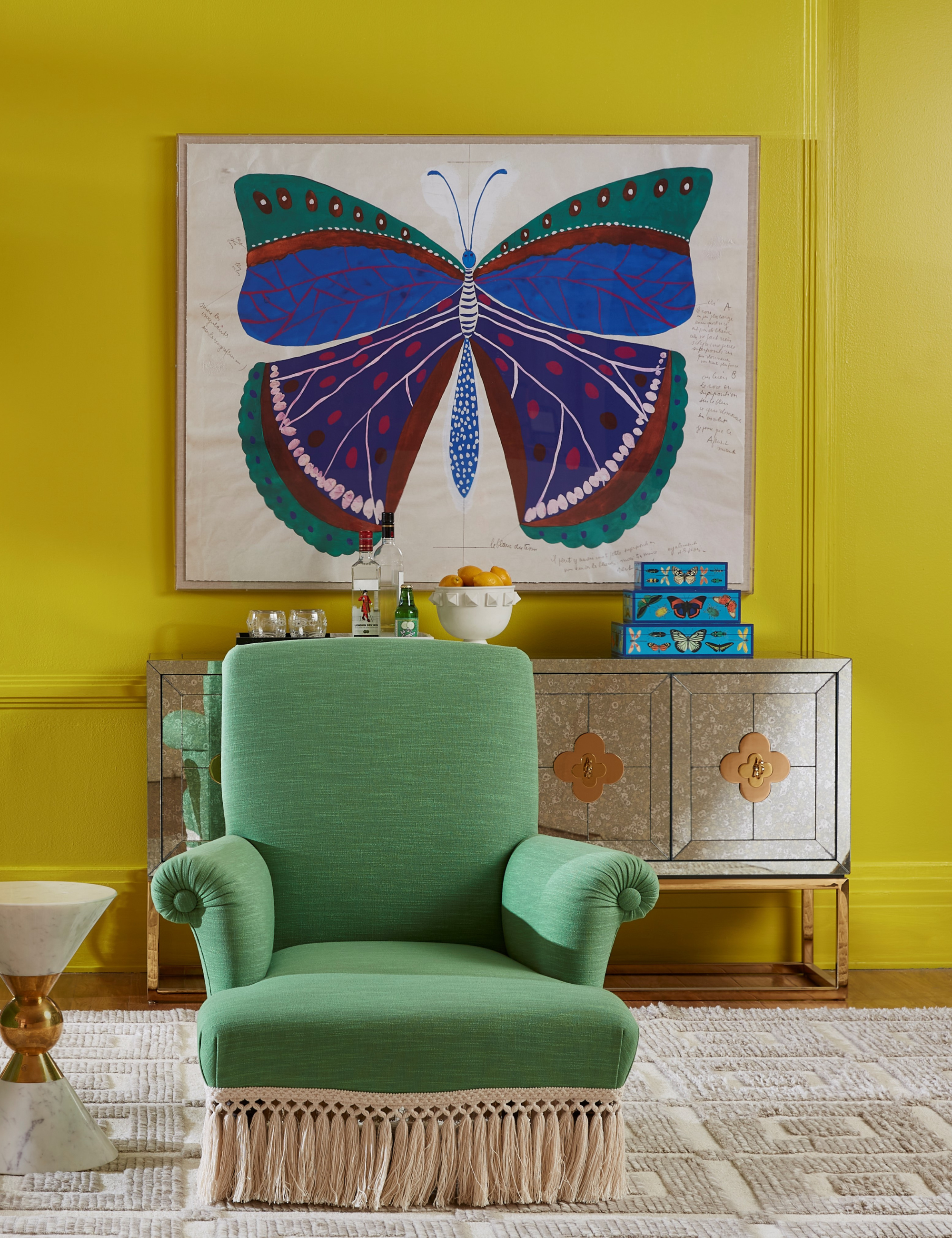 Chartreuse living room area featuring butterfly wall art and a green fringe-bordered accent chair