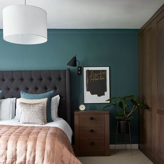 teal bedroom with carpet flooring and bedside table