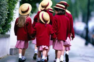 A group of children walking to school wearing straw boater hats