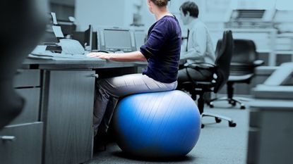 Woman sitting at her desk on a yoga ball.