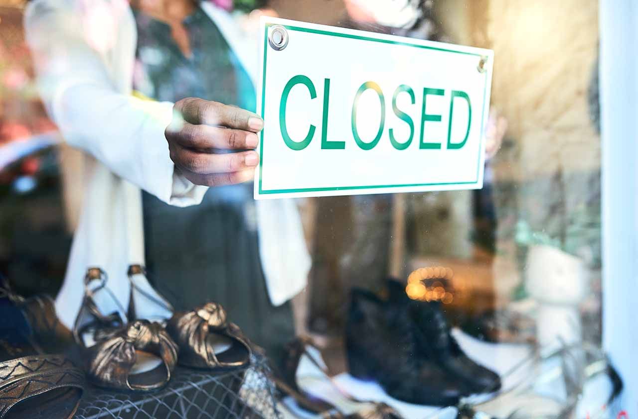 Cropped shot of an unrecognizable woman holding up a closed sign