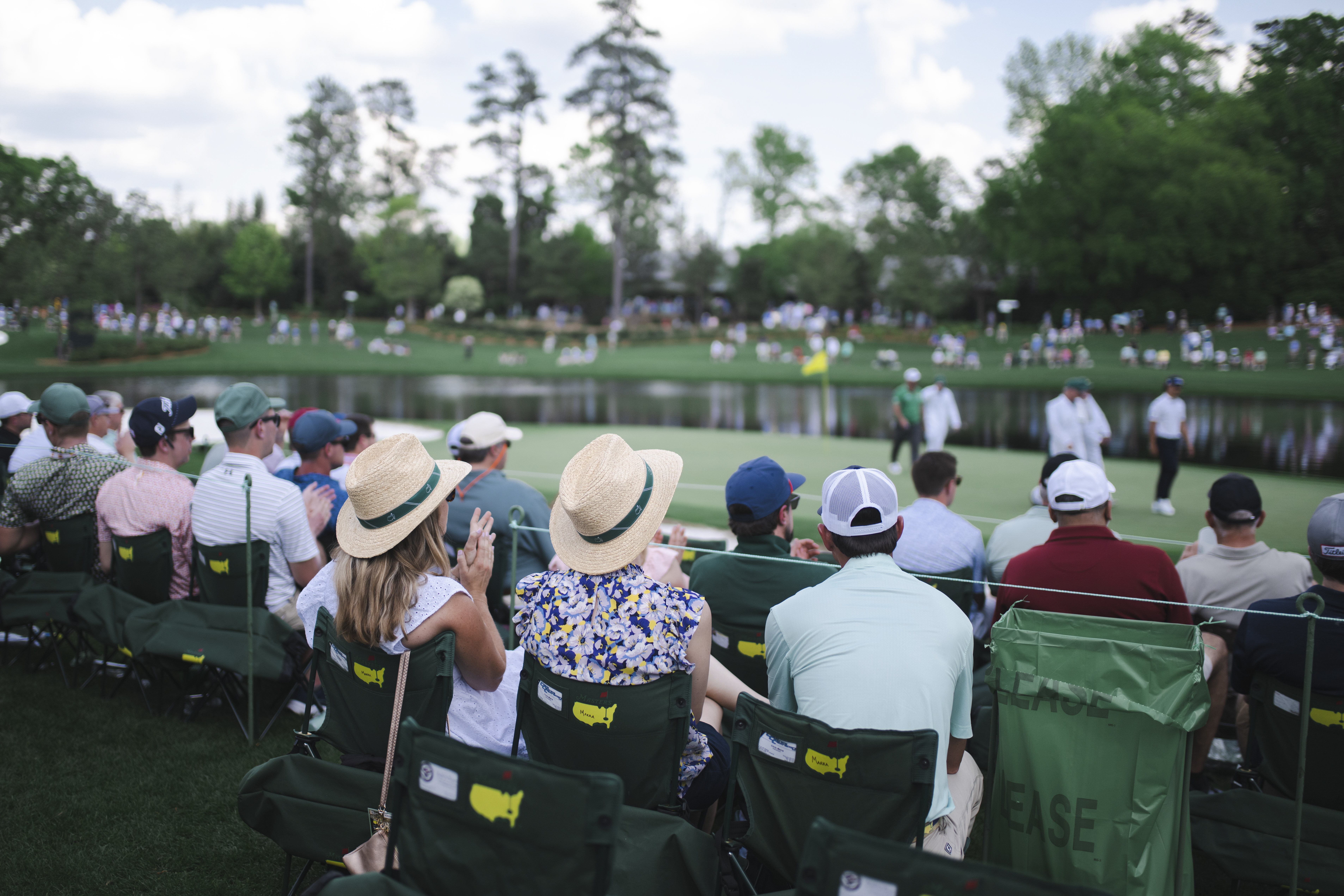 A view from behind patrons sitting on chairs at the 16th green during The Masters