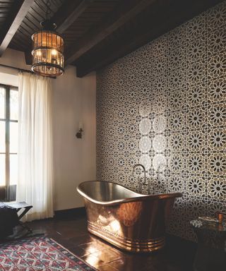 bathroom with moroccan tiles on walls and freestanding copper tub and lantern