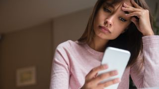 Woman using mobile phone looking frustrated