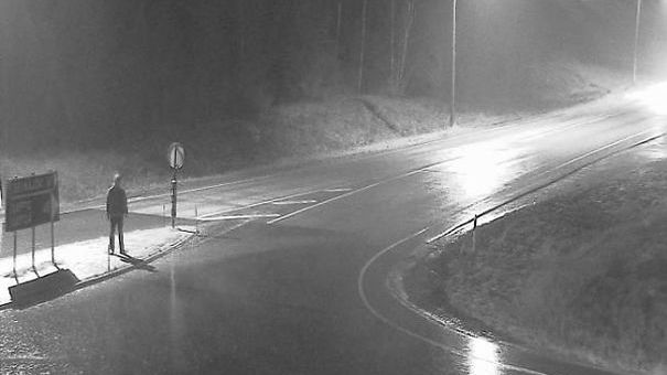 Tatu Gustafsson stands on a dark wide road and is photographed by a weather camera 