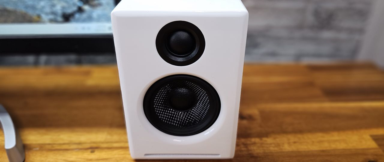 Front of white A2+ speaker on wooden desk.