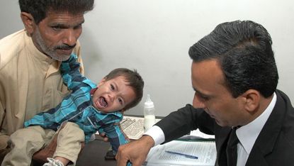 Nine-month-old, Mohammad Musa, has his fingerprints taken by a Pakistani lawyer