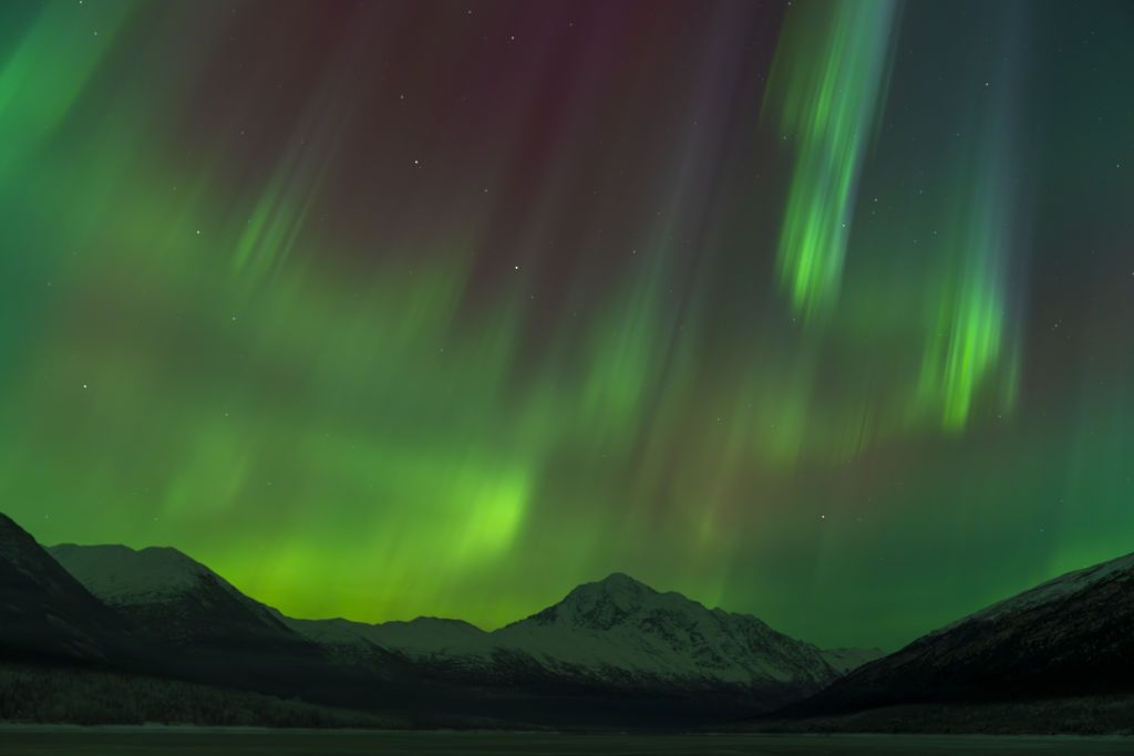 northern lights above alaska during new year's celebrations. large ribbons of green light dance through the sky.