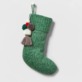 green knitted christmas stocking with pom poms