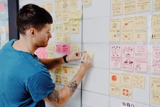 Man sticking post-its with ideas and illustrations onto a board