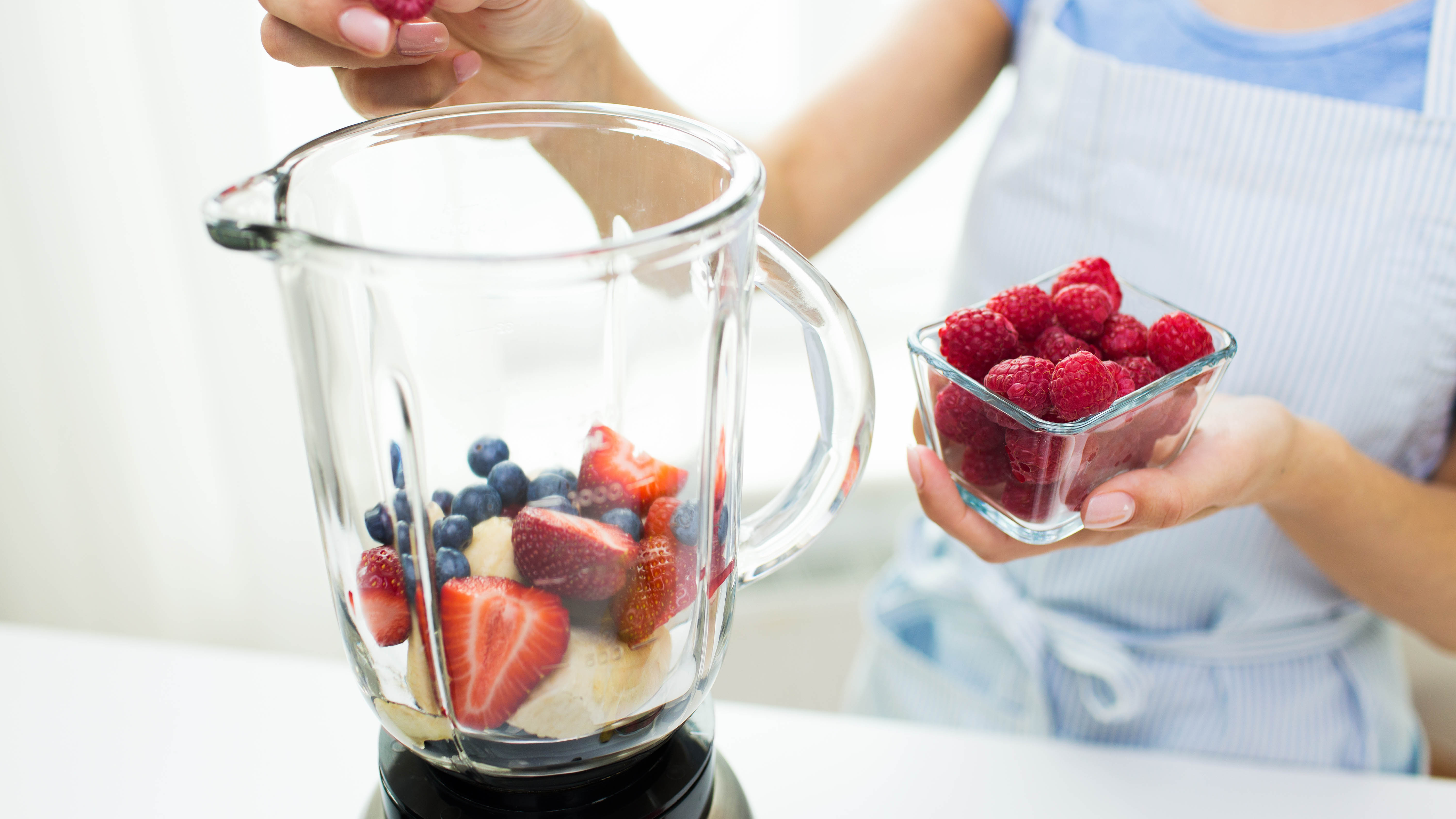 Woman putting fruit into a blender