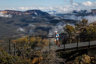 A man running across a bridge with views of a mountain range in the distance