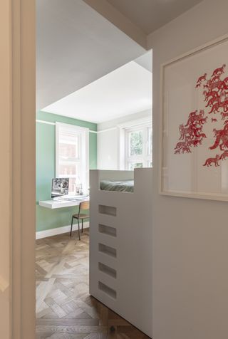 teen room with bespoke bed, green wall, floating desk, parquet floor, artwork outside door